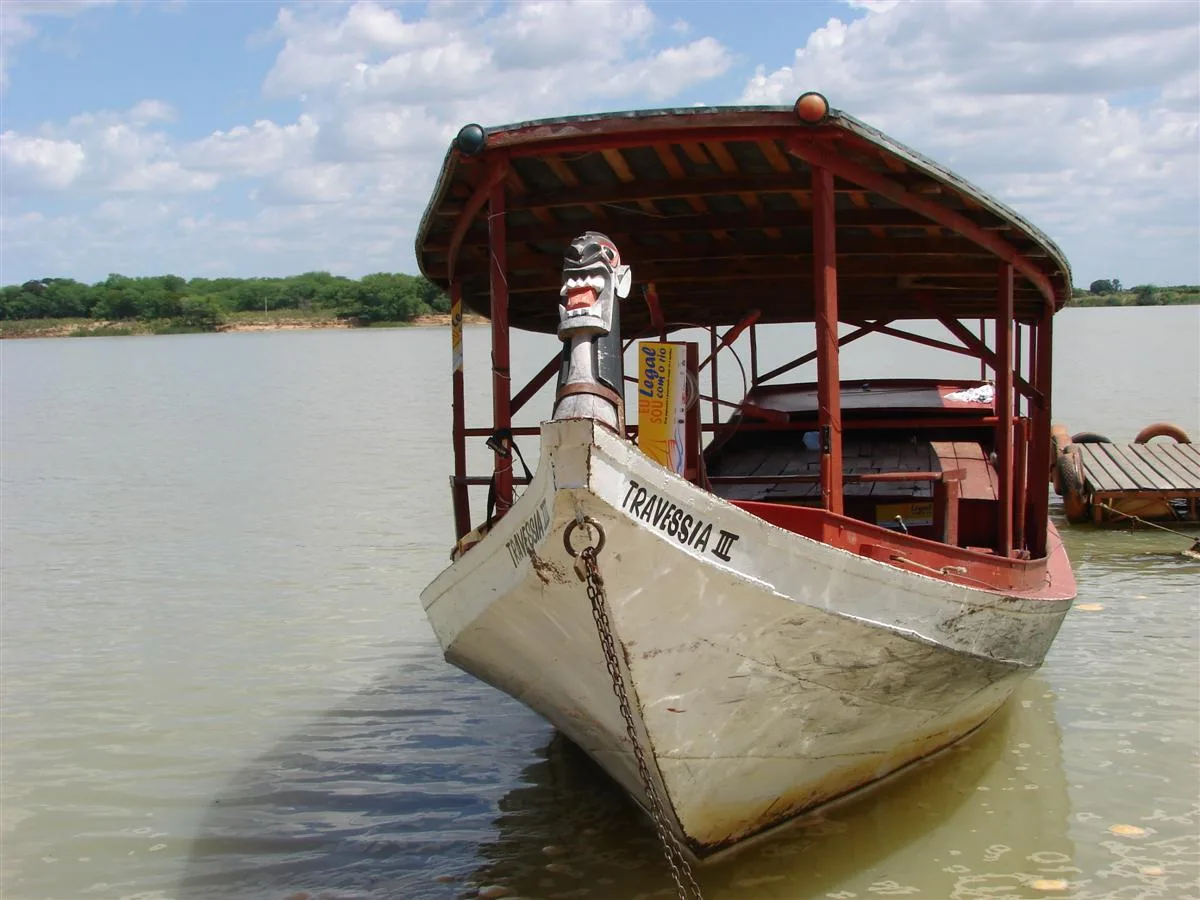 Barco de madeira com toldo vermelho e uma carranca na proa, ancorado nas águas do Rio São Francisco