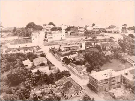 Fotografia antiga em tons sépia do centro de São Pedro da Aldeia visto do alto, com casas baixas e um sobrado