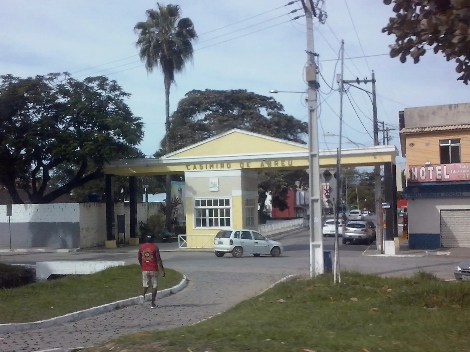 Construção de entrada da cidade de Casimiro de Abreu, com telhado e palmeira, à beira da avenida