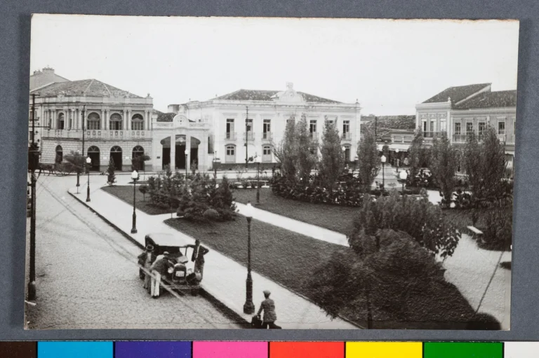 Cartão-postal antigo em preto e branco de uma praça arborizada de Guaratinguetá, com casarões e sobrados ao redor