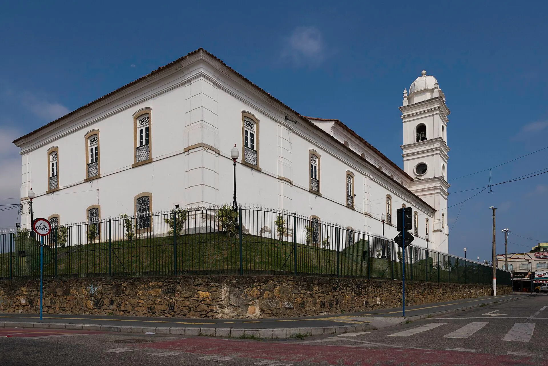 Igreja Matriz de Nossa Senhora do Amparo, construção colonial branca com longa fachada lateral e torre sineira, no centro de Maricá