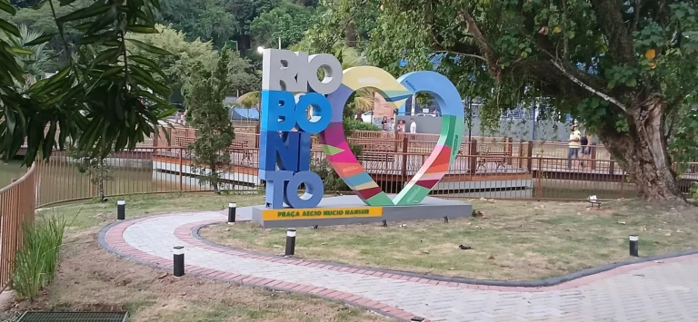 Letreiro colorido com o nome Rio Bonito e um coração, em meio ao gramado e às árvores da Praça Aécio Múcio Mansur, no bairro Green Valley