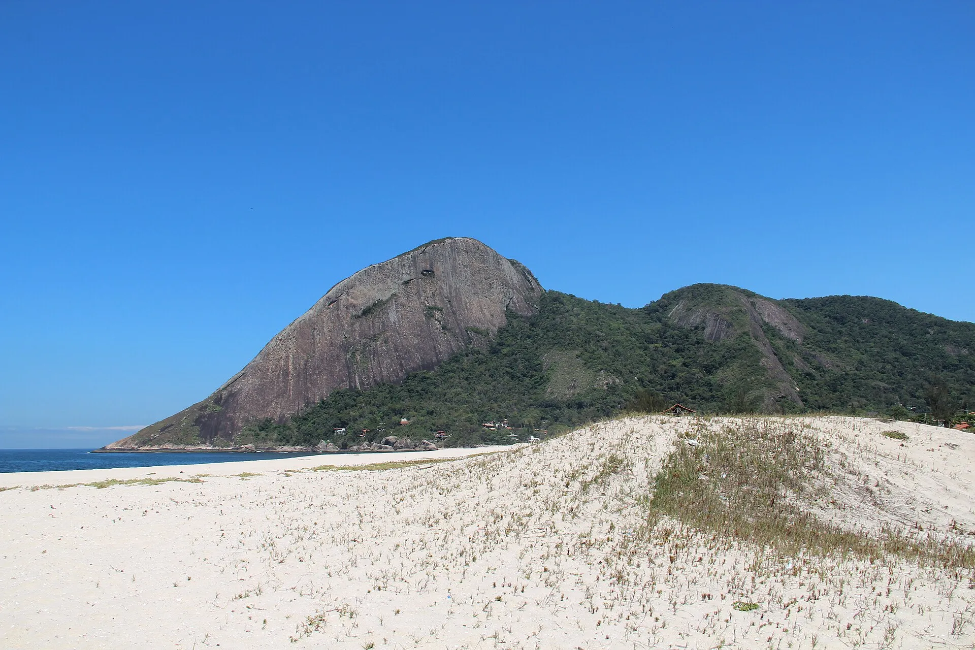 Pedra do Elefante, montanha de granito com vegetação, vista a partir das dunas da Praia de Itaipuaçu sob céu azul