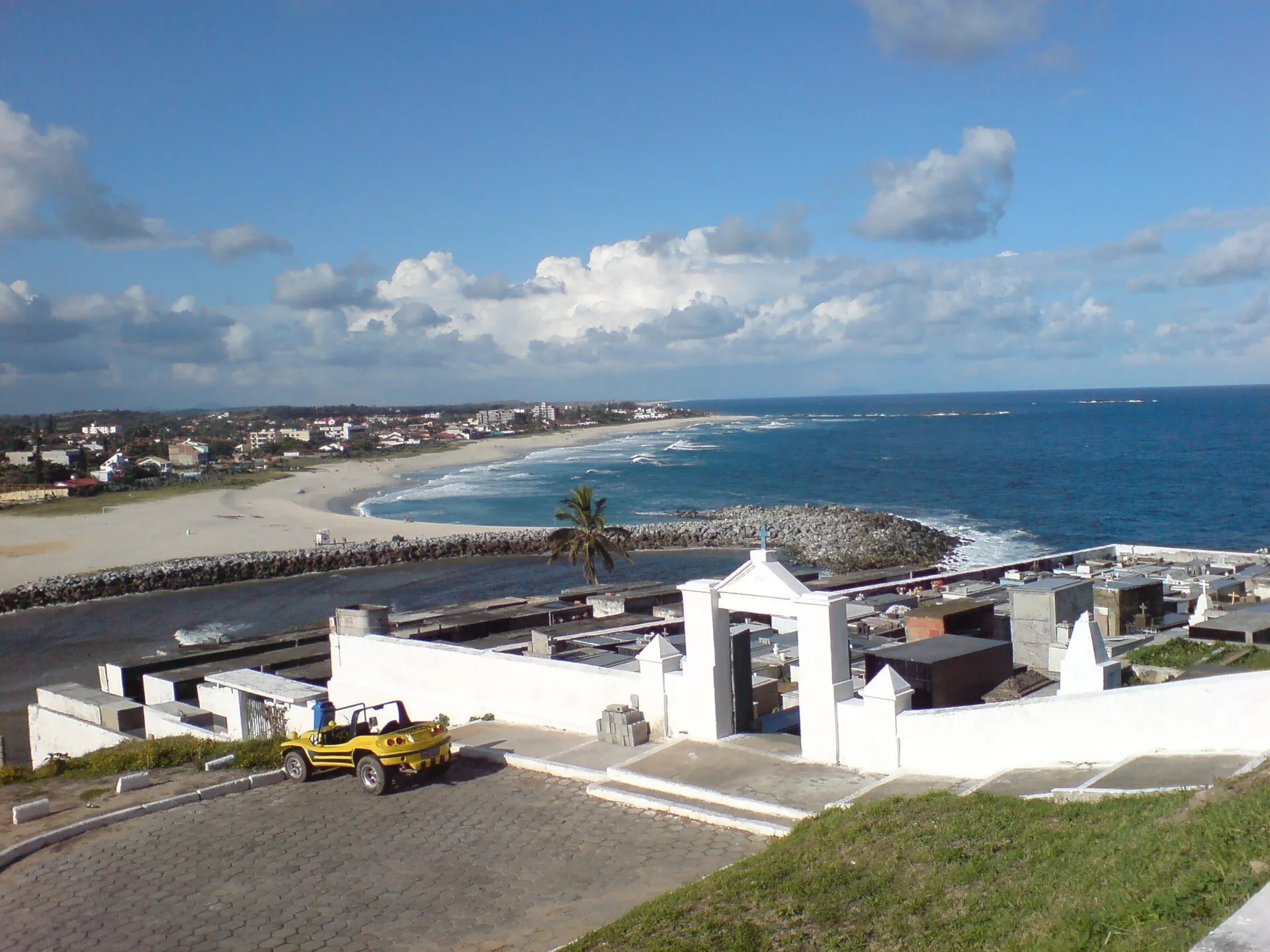 Vista do alto do morro da igreja para a Praia de Itaúna, com o muro branco do cemitério antigo em primeiro plano