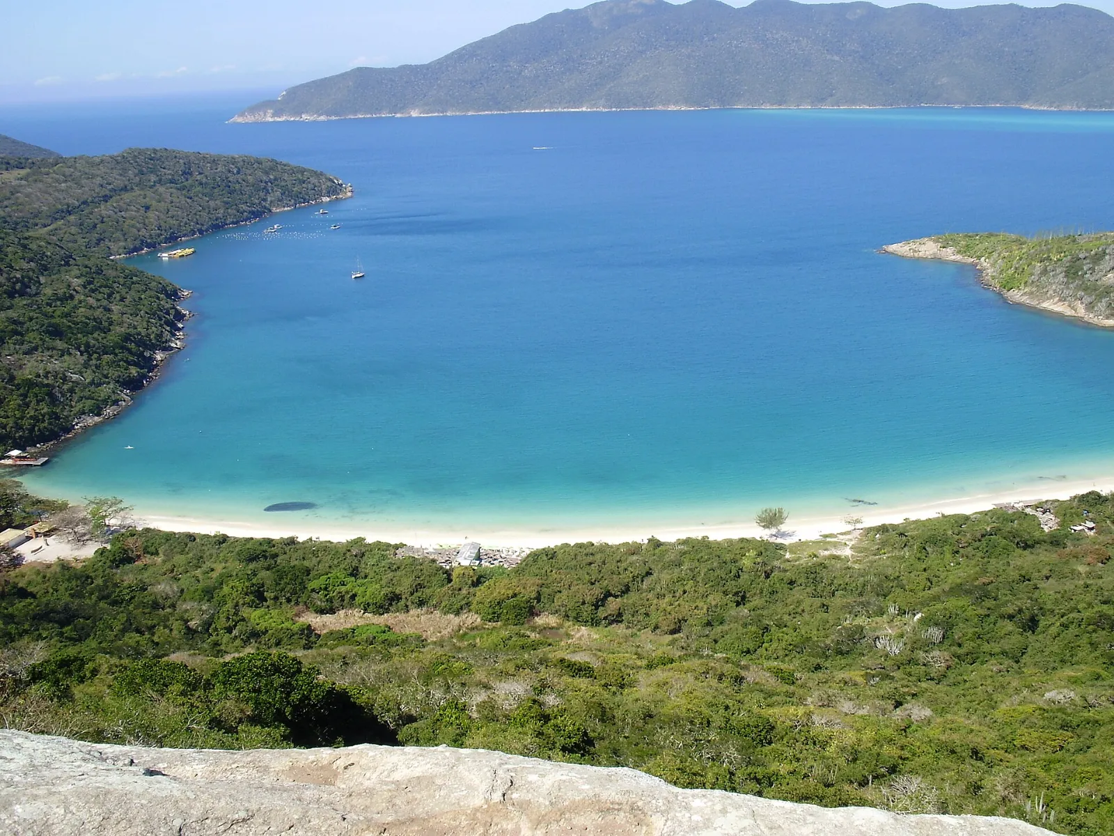 Vista do alto da Praia do Forno, enseada de águas claras cercada de vegetação em Arraial do Cabo