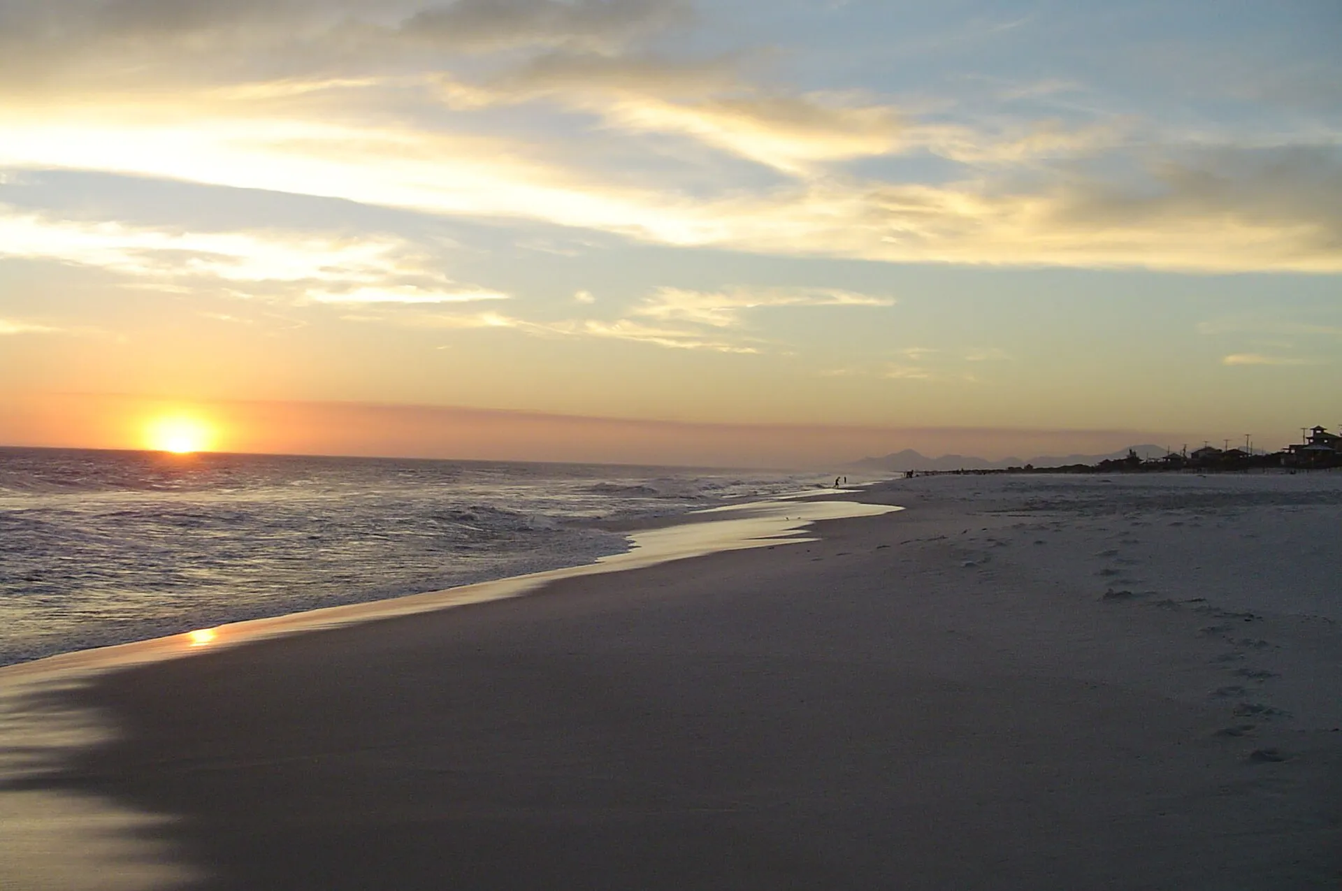 Pôr do sol sobre o mar aberto na Praia Seca, com faixa larga de areia clara