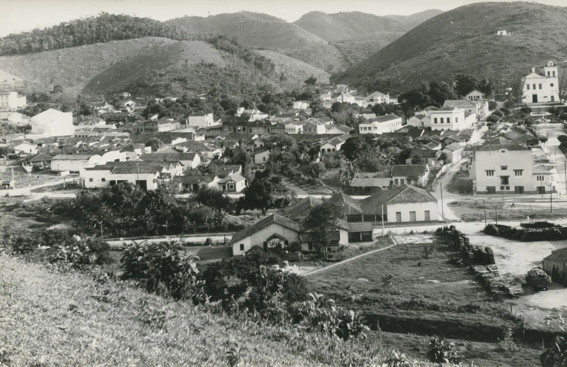 Fotografia em preto e branco da cidade de Rio Bonito em 1972, com casas espalhadas pelo vale e morros ao fundo