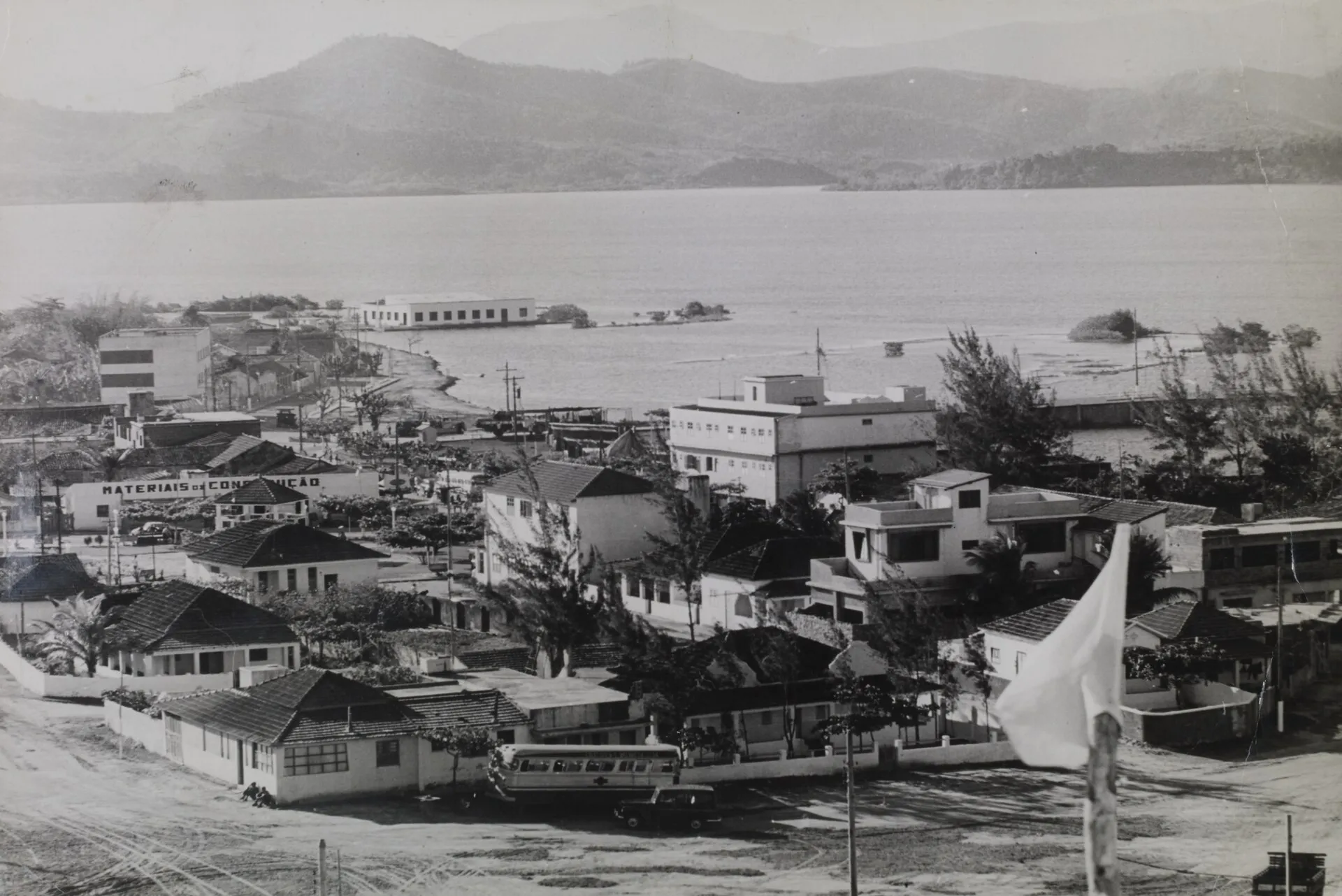 Fotografia em preto e branco de Saquarema em 1968, com casas baixas, a lagoa e morros ao fundo
