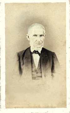Retrato fotográfico antigo de um homem idoso de cabelos brancos, terno escuro e gravata-borboleta