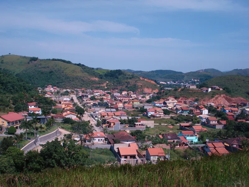 Vista do alto de bairro de Rio Bonito, com casas de telhado vermelho entre morros verdes